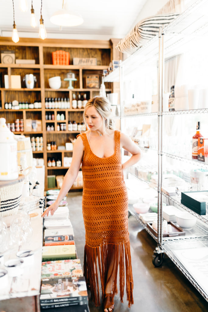 How to Wear Hair Clips by popular Nashville fashion blog, Nashville Wifestyles: image of a woman with a braided hairstyle and wearing a pearl letter H hair clip, gold bobby pins, and a star hair clip in her hair along with an orange crocheted maxi dress with fringe.