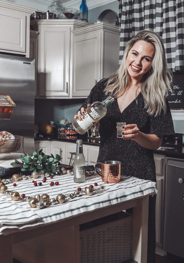 Holiday Moscow Mule || Apple Cranberry by popular Nashville life and style blog, Nashville Wifestyles: image of a woman making a holiday Moscow Mule in her kitchen.