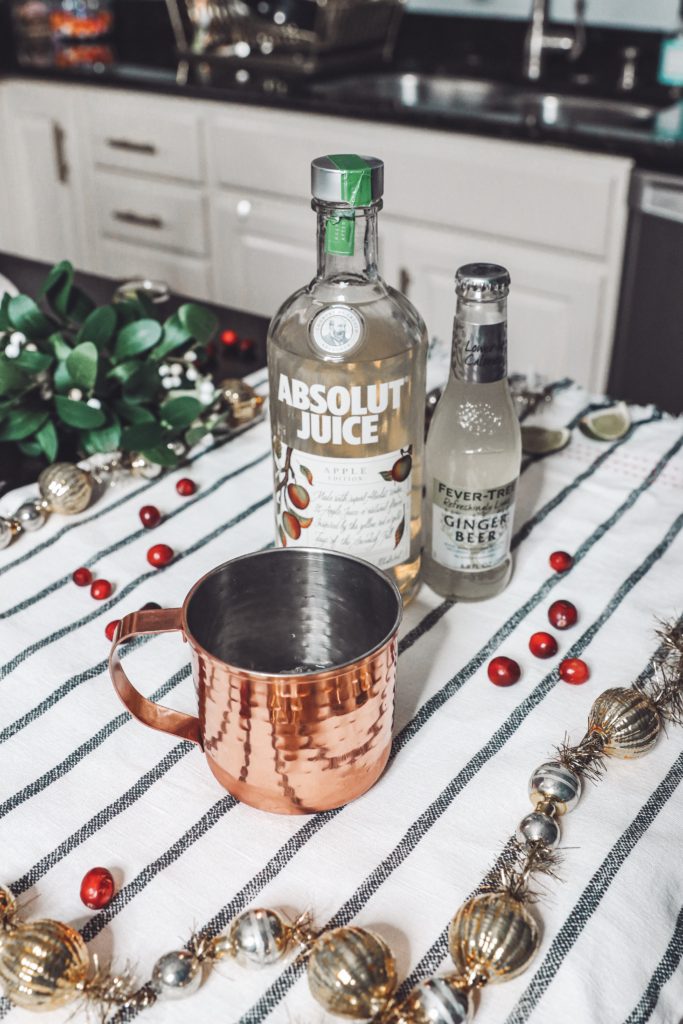 Holiday Moscow Mule || Apple Cranberry by popular Nashville life and style blog, Nashville Wifestyles: image of a copper mug, cranberries, Absolut Juice and Ginger Beer.