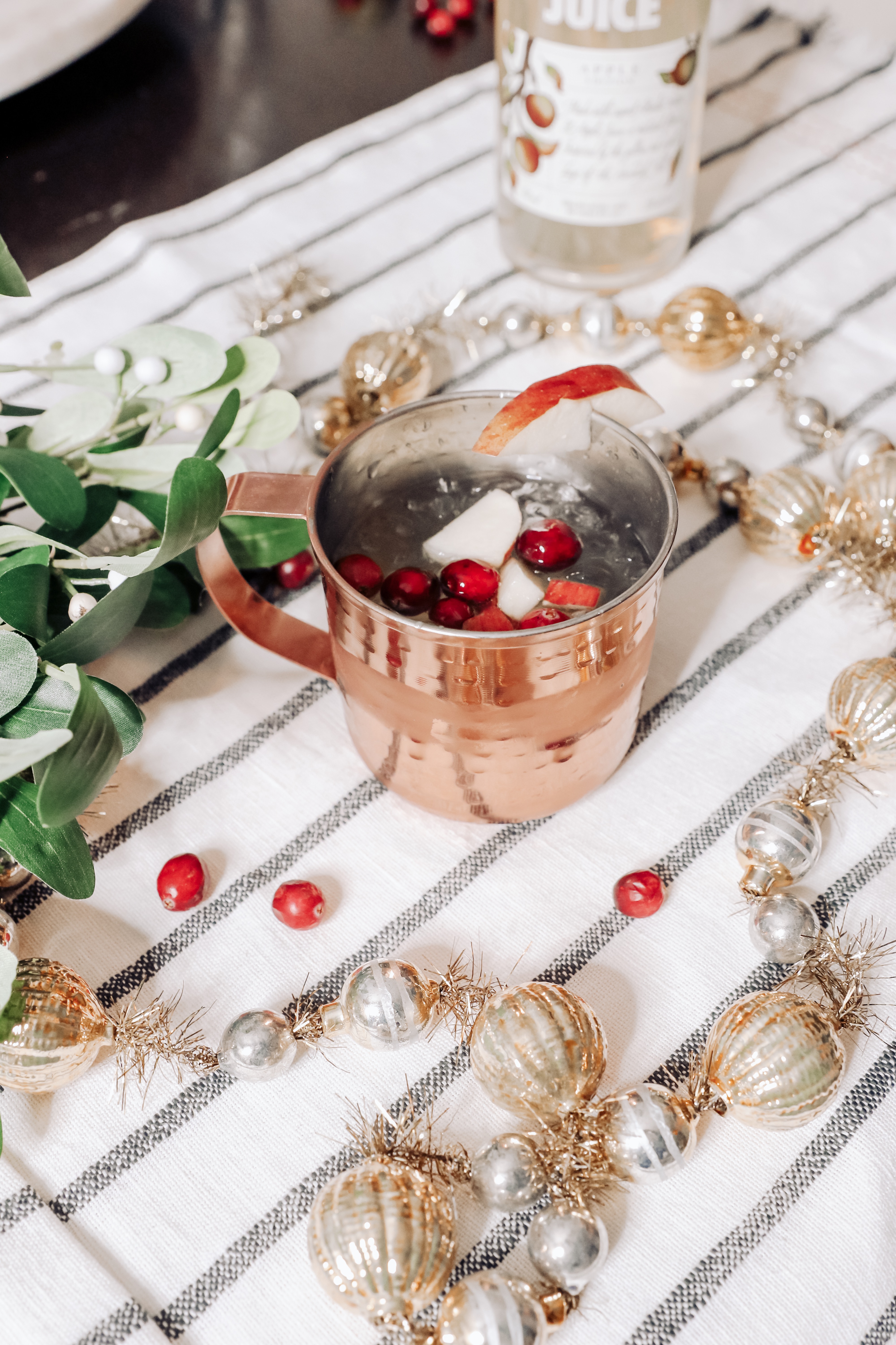 Holiday Moscow Mule || Apple Cranberry by popular Nashville life and style blog, Nashville Wifestyles: image of a copper mug filled with a holiday Moscow Mule.