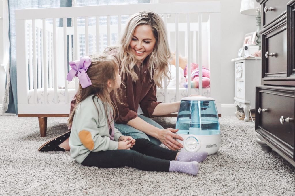Soothe Coughs & Sore Throats with Vick's Filter Free Cool Mist Humidifier by popular Nashville life and style blog, Nashville Wifestyles: image of a mom adjusting the settings on the  Vick's filter free cool mist humidifier.