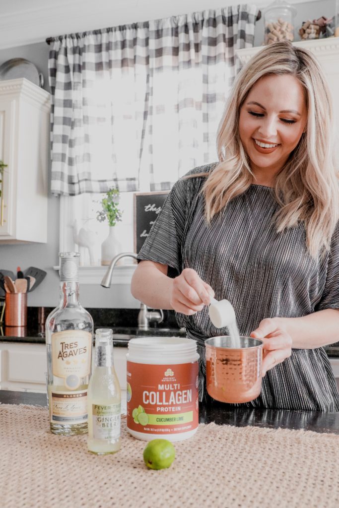 Cucumber Lime Mexican Mule Recipe || Collagen Cocktail by popular Nashville life and style blog, Nashville Wifestyles: image of a woman making a Mexican Mule cocktail with Tres Agaves and Ancient Nutrition multi Collagen protein powder.