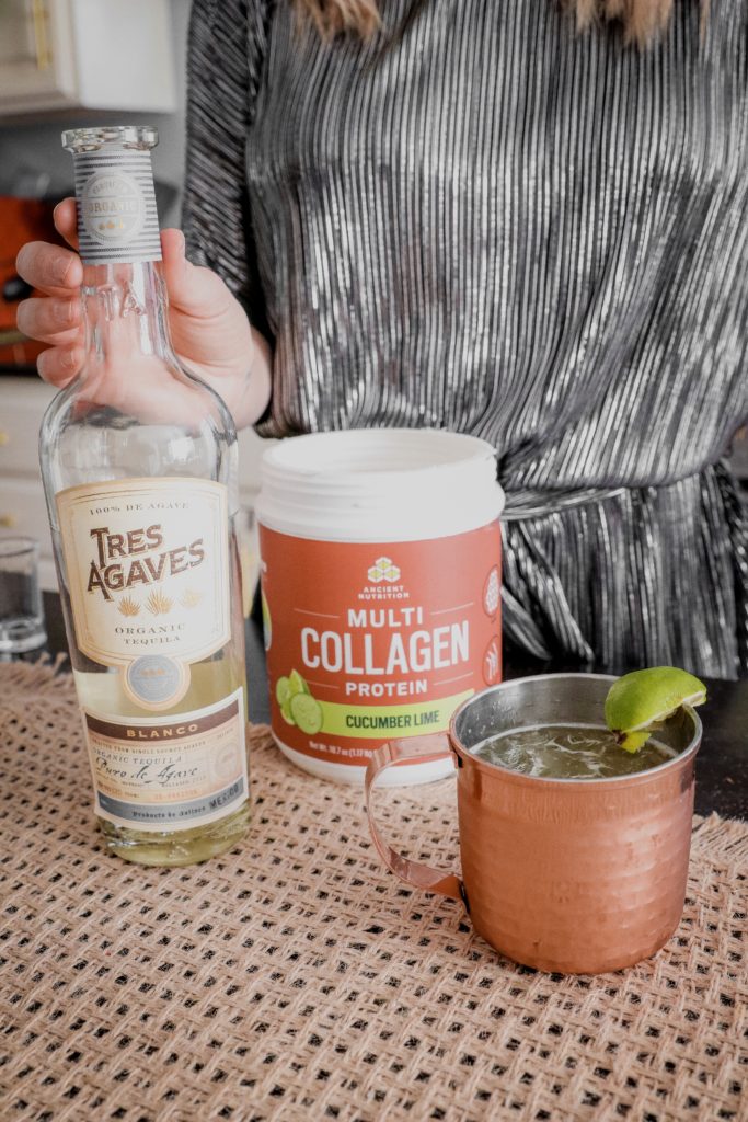 Cucumber Lime Mexican Mule Recipe || Collagen Cocktail by popular Nashville life and style blog, Nashville Wifestyles: image of a woman making a Mexican Mule cocktail with Tres Agaves and Ancient Nutrition Collagen powder.