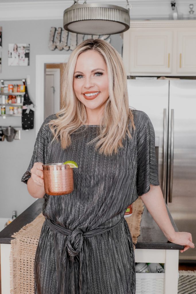 Cucumber Lime Mexican Mule Recipe || Collagen Cocktail by popular Nashville life and style blog, Nashville Wifestyles: image of a woman holding a copper mug filled with a Mexican Mule cocktail. 