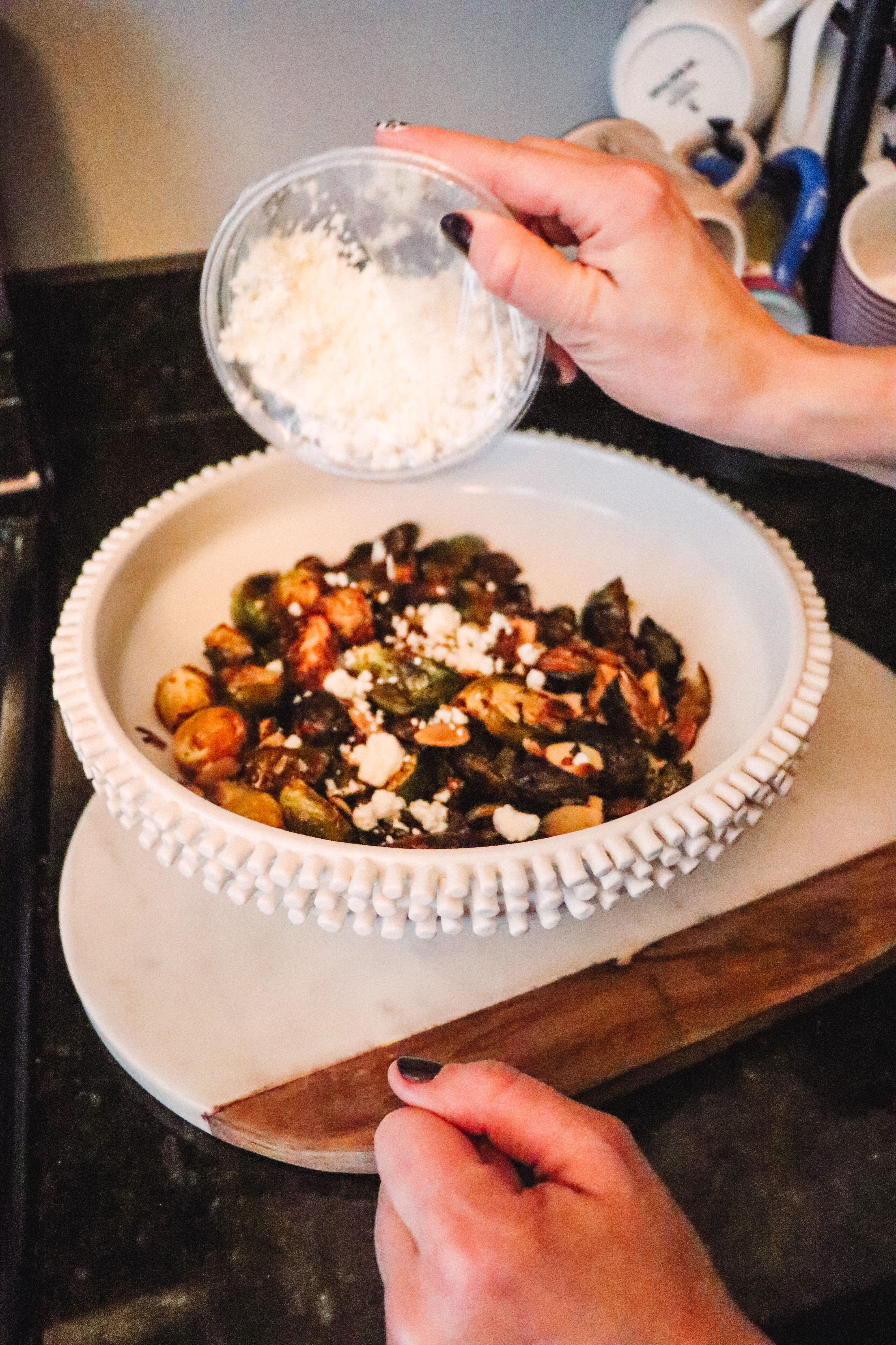 Honey Roasted Brussel Sprouts by popular Nashville life and style blog, Nashville Wifestyles: image of a woman goat cheese on honey roasted Brussel sprouts.