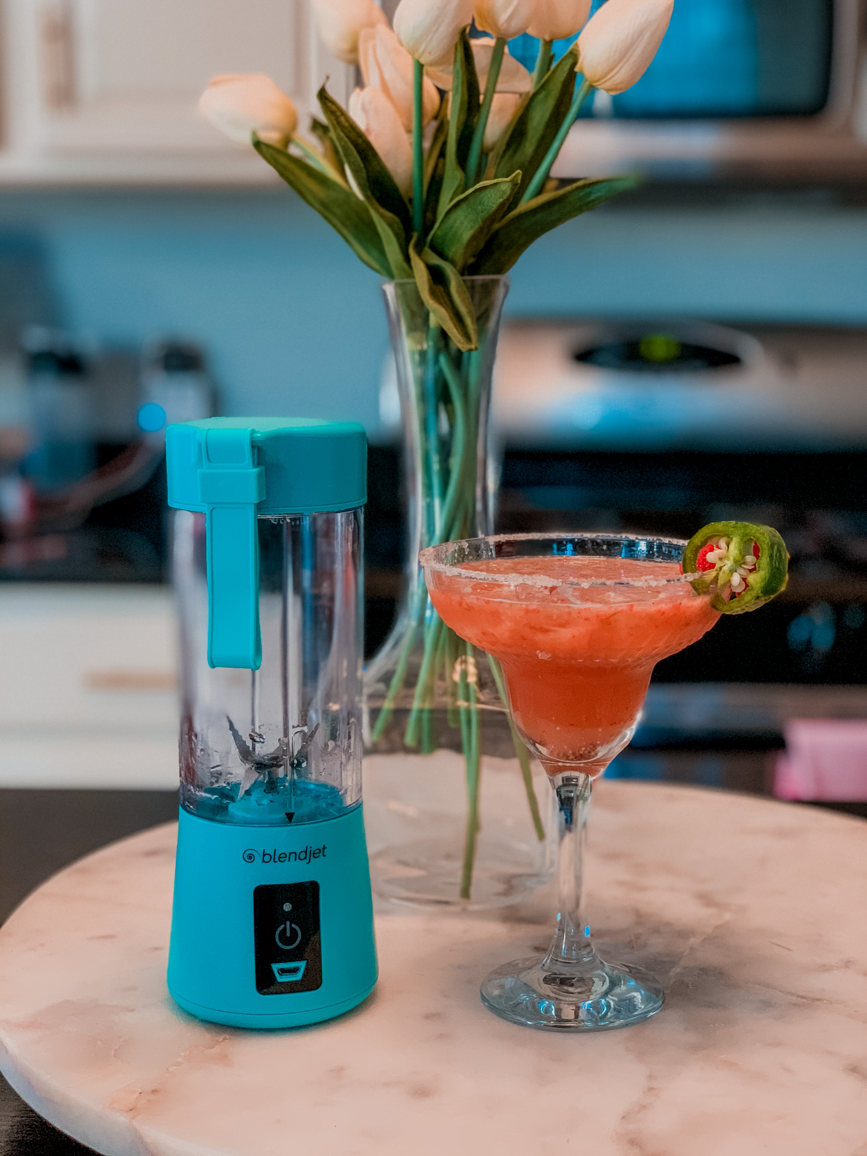 Skinny Margarita Recipe by popular Nashville lifestyle blog, Nashville Wifestyles: image of a drink blender next to a spicy strawberry jalapeno margarita in a margarita glass.